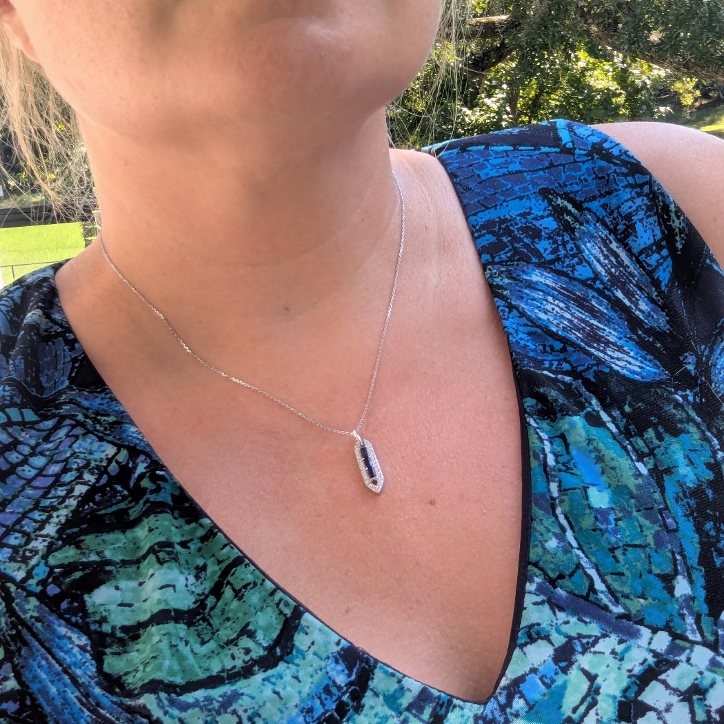 Person wearing a blue patterned top with a necklace outdoors